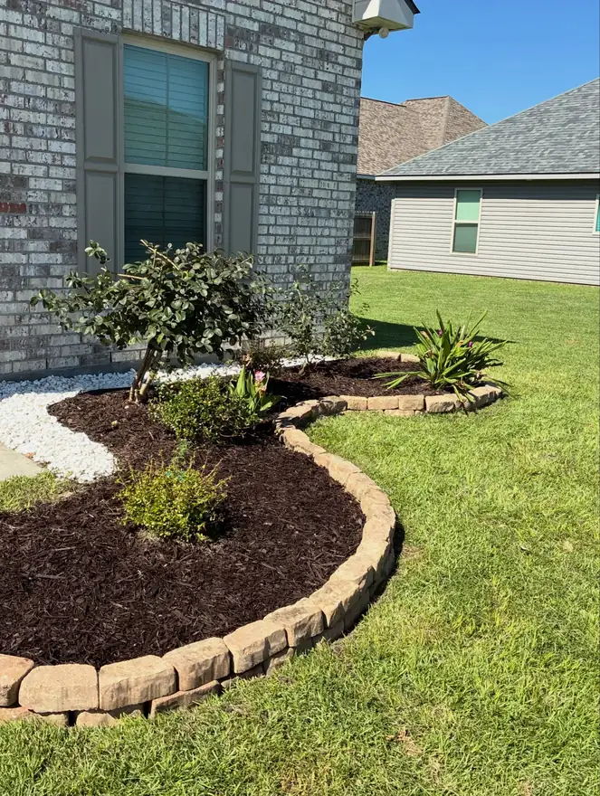 Curved mulch bed with stone edging and white rock