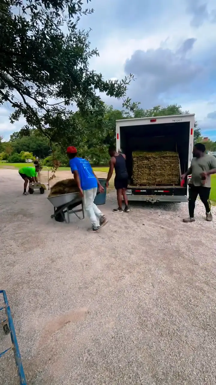 Tre's crew moving material by wheelbarrow from the truck