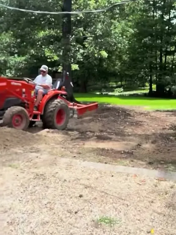 Tre grading bare dirt level on a red tractor before the sod goes down